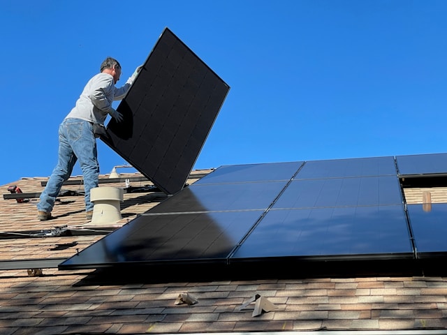 Fachkraft bei der Installation und Wartung von Photovoltaikmodulen auf einem Dach unter klarem Himmel